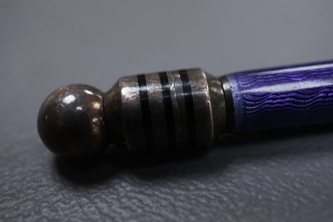A silver and purple guilloche enamel pen, with ringed black enamel and globe terminals, one unscrews to reveal the pen tip, hallmarks beneath the enamel, possibly London, 1979, 13.9cm.